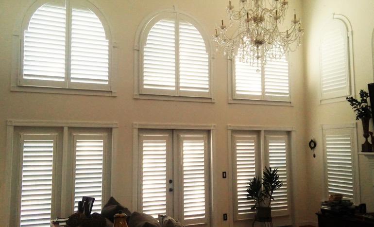 Television room in two-story Jacksonville house with plantation shutters on high windows.