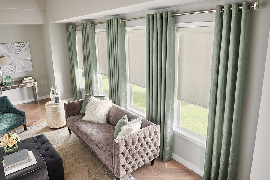 White roller shades paired with green curtains in a living room