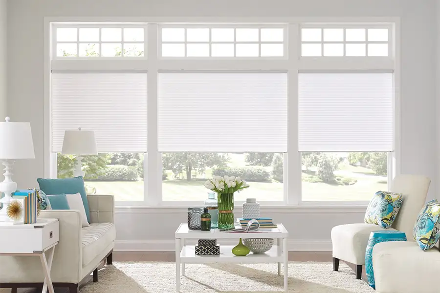 Insulating cellular shades can help keep cold air and hot UV rays from entering your Jacksonville home. White cellular shades on windows in a white living room